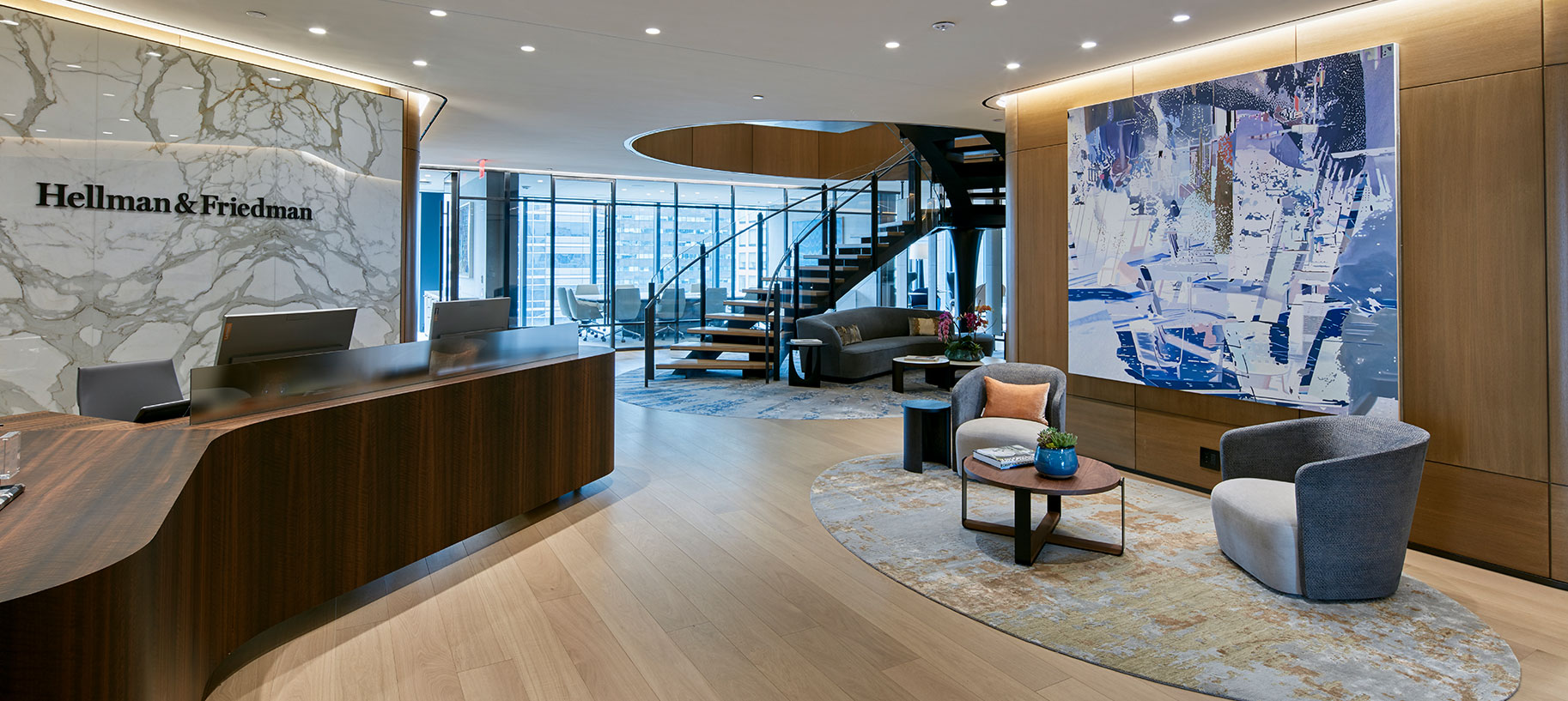 A contemporary office interior design featuring a sleek dark wood reception desk, marble slab reception logo wall, and stylish seating. The large scale contemporary painting is part of the client's significant all-minority-artists collection. A striking oval spiral staircase leads up to the private office level.