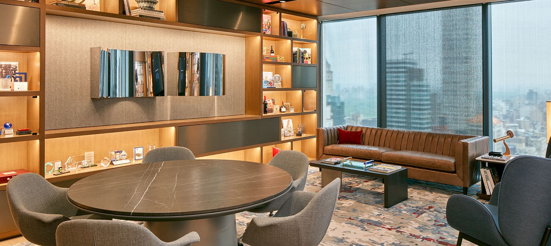 This private Library meeting room is the most popular space in the new Hellman & Friedman office with staff - it's inviting warm tone is set by generous built in shelving, a vibrant custom contemporary rug, and comfortable seating. This hospitality flavored room is both a fully functional telepresence meeting space and comfortable lounge in one.