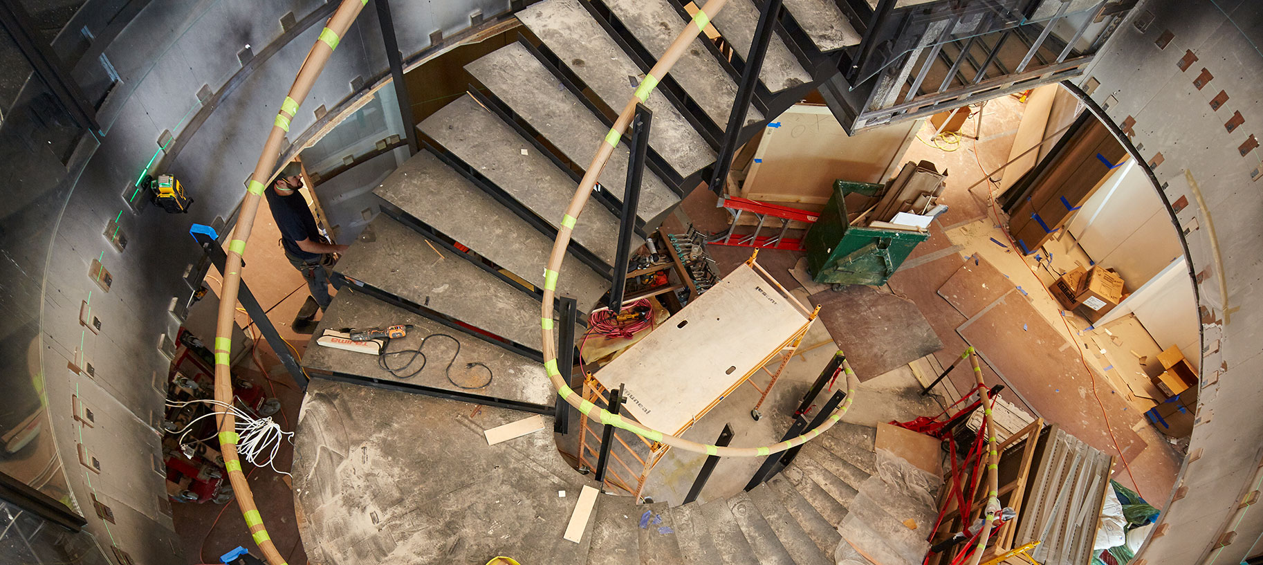 During construction two separate floors were joined together in this new skyscraper, with an oval staircase opening punching through the floor plates to allow and open movement flow crucial for contemporary interior design. This image shows detail of the spiral staircase within a building under construction, highlighting the framework and unfinished surroundings.