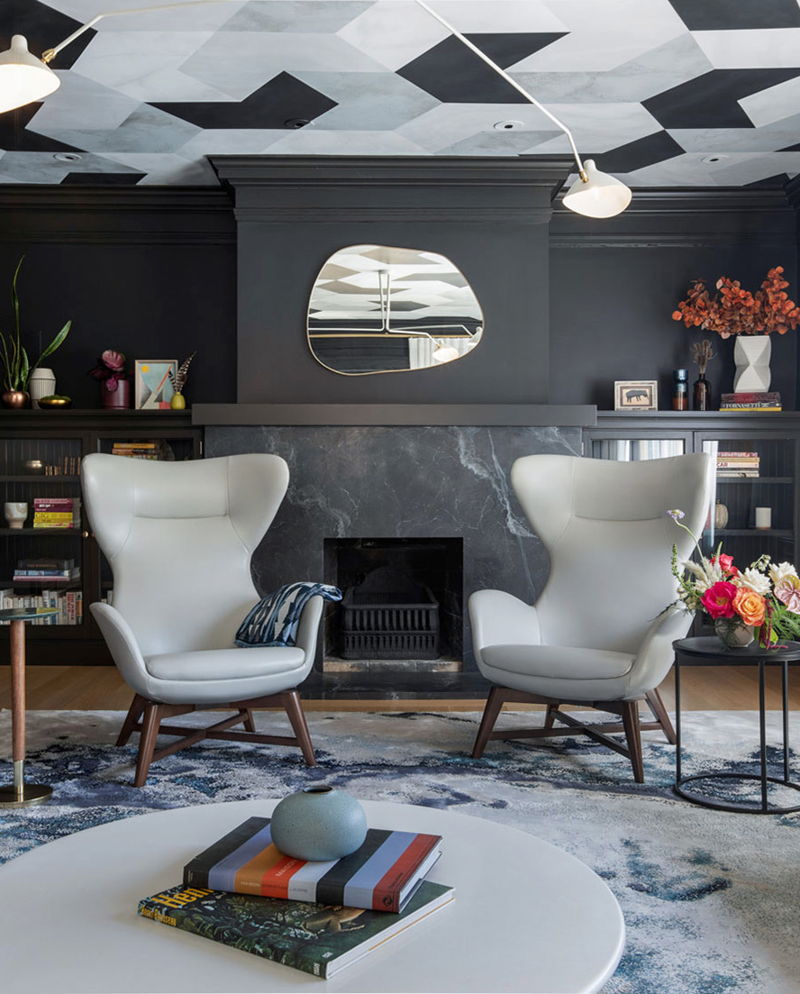 A modern living room featuring striking black walls and a black marble slab fireplace surround, complemented by elegant white furniture, creates contrast for a bold interior design.